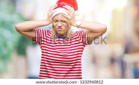 Young beautiful blonde woman wearing christmas hat over isolated background suffering from headache desperate and stressed because pain and migraine. Hands on head.