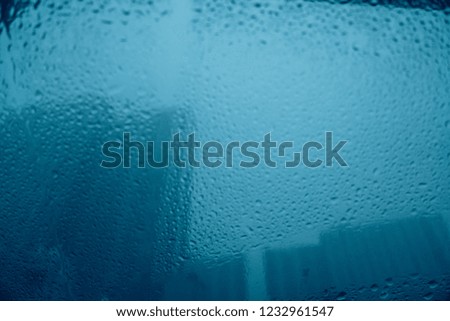 Blurred image of drops of rain on mirror with buildings and road. Using as background.