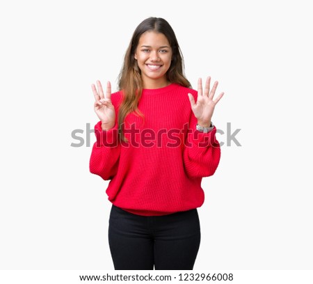 Young beautiful brunette woman wearing red winter sweater over isolated background showing and pointing up with fingers number eight while smiling confident and happy.