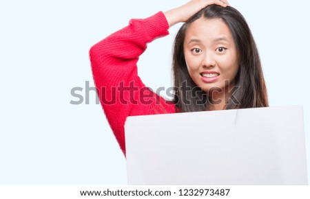 Young asian woman holding banner over isolated background stressed with hand on head, shocked with shame and surprise face, angry and frustrated. Fear and upset for mistake.