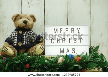merry Christmas word on light box with teddy bear and green tinsel decoration