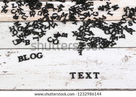 a heap of black wooden letters are lying on the table and create the words blog and text