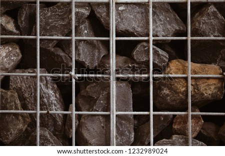Photo of rocks in side metal net