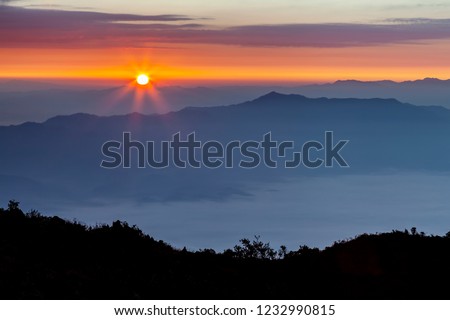 Mountain range in morning sunrise with sun flare.Sea of fog foreground with Silhouette of hill .Photo form summit of Doi Luang Chiang dao, Chiangmai, Thailand.