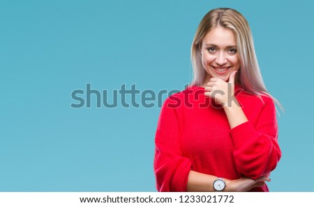 Young blonde woman wearing winter sweater over isolated background looking confident at the camera with smile with crossed arms and hand raised on chin. Thinking positive.