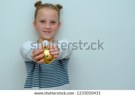 Beautiful smiling young teenage girl over grey background. Child holding illuminating yellow baubles decoration for Christmas tree. Selective focus on Christmas ball.