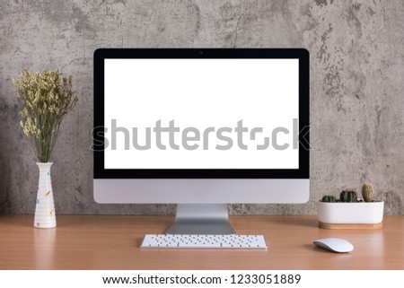 Blank screen of all in one computer with dry flowers and cactus vase on raw concreate background