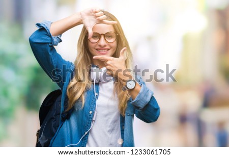 Young beautiful blonde student woman wearing headphones and glasses over isolated background smiling making frame with hands and fingers with happy face. Creativity and photography concept.
