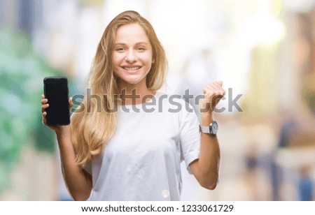 Young beautiful blonde woman showing screen of smartphone over isolated background screaming proud and celebrating victory and success very excited, cheering emotion