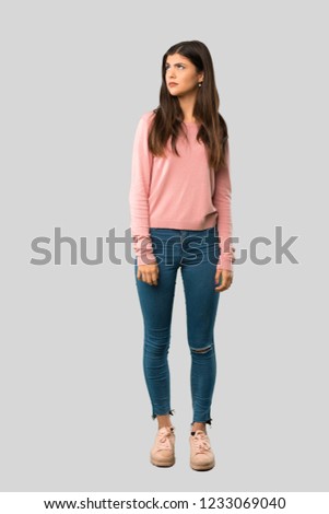 Full body of Teenager girl with pink shirt is a little bit nervous and scared pressing the teeth on isolated grey background