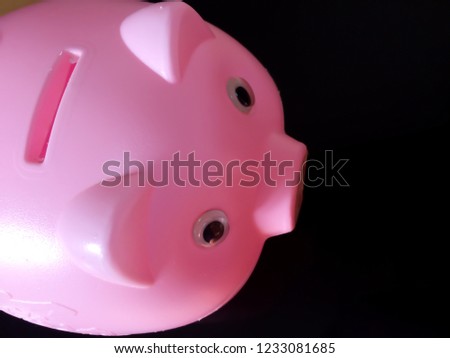 Pink piggy bank for savings with black background.