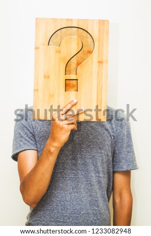 man holding a wooden board with a question mark
