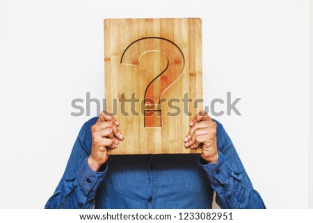 man holding a wooden board with a question mark