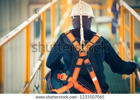 Construction worker wearing safety harness and safety line working at high place Royalty-Free Stock Photo #1233107065
