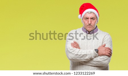 Handsome senior man wearing christmas hat over isolated background skeptic and nervous, disapproving expression on face with crossed arms. Negative person.