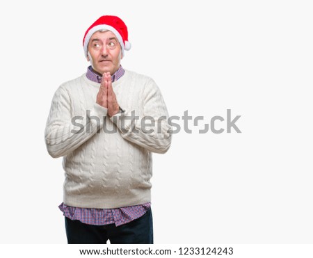 Handsome senior man wearing christmas hat over isolated background praying with hands together asking for forgiveness smiling confident.