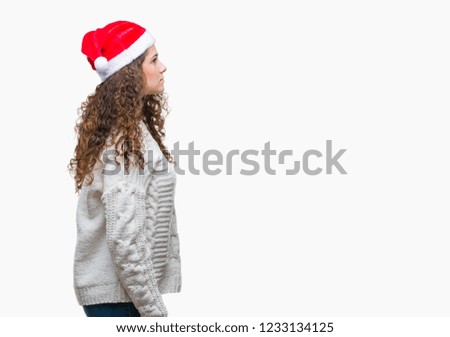 Young brunette girl wearing christmas hat over isolated background looking to side, relax profile pose with natural face with confident smile.