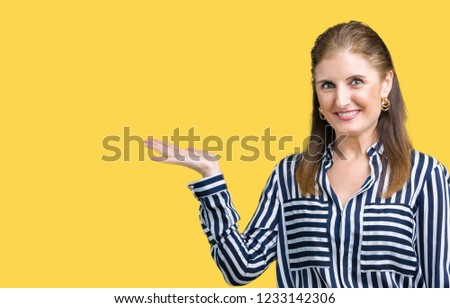 Middle age mature business woman over isolated background smiling cheerful presenting and pointing with palm of hand looking at the camera.