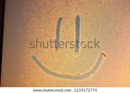 Smile image on freezen window. Picture on the Iced water drops. Winter painting