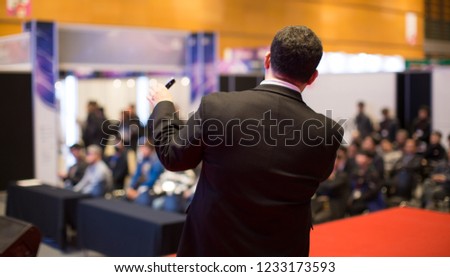 Presenter Presenting on Stage at Conference Meeting. Speaker at Professional Lecture. Unidentifiable Blurred De-focused. Tech Presenter and Audience. Corporate Executive Manager Presentation Seminar.
