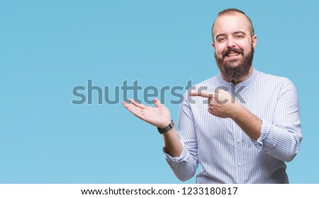Young caucasian hipster man over isolated background amazed and smiling to the camera while presenting with hand and pointing with finger.