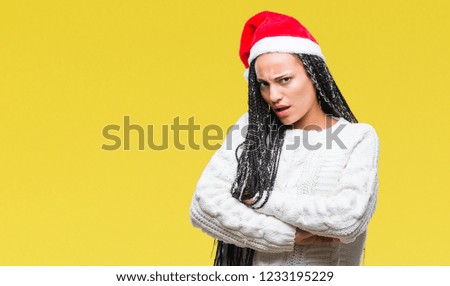 Young braided hair african american girl wearing christmas hat over isolated background skeptic and nervous, disapproving expression on face with crossed arms. Negative person.