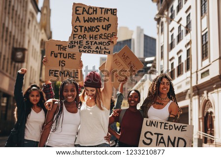 Group of protesters enjoying during a women's march with signboards. Laughing women holding protest signs for women power and future