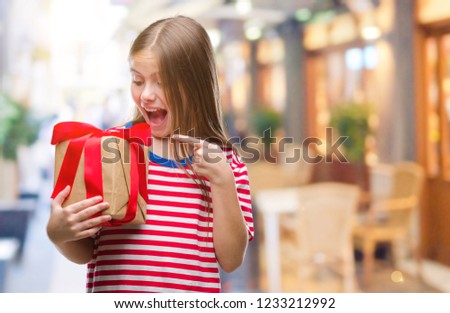 Young beautiful girl giving christmas or valentine gift over isolated background very happy pointing with hand and finger