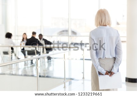 Rear view at stressed nervous middle aged senior old business woman applicant waits for job interview holding papers behind back preparing for performance feel afraid of public speaking fear concept Royalty-Free Stock Photo #1233219661