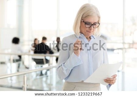 Nervous middle aged old businesswoman feeling scared stressed afraid waiting for job interview, worried mature senior applicant or speaker reading papers preparing for public speaking fear concept Royalty-Free Stock Photo #1233219667
