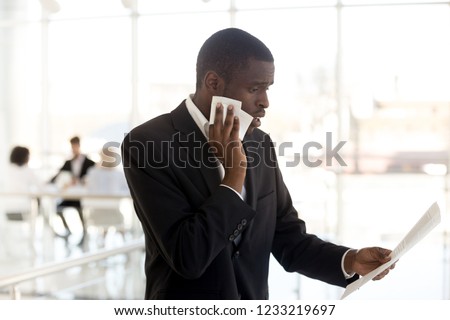 Scared nervous african american businessman sweating wiping face feeling stressed afraid waiting for job interview, worried black male speaker reading paper preparing for public speaking fear concept Royalty-Free Stock Photo #1233219697