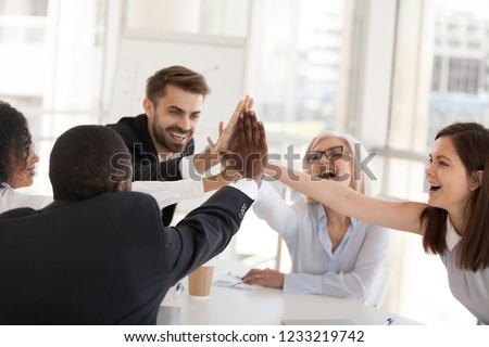 Excited multiracial office associates employees group giving high five engaged in coaching team spirit, motivated by unity, involved in good corporate relations celebrate business success concept Royalty-Free Stock Photo #1233219742