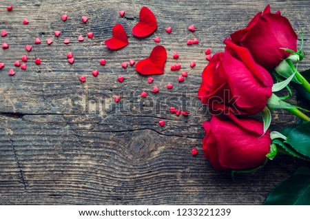 Red roses flowers with red hearts on old wooden background with place for text. Romantic Valentines holidays concept. Valentine's day greeting card. Copy space. Top view.