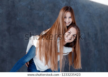 Stylish beautiful mother and a cute daughter with blue eyes in studio hugging and having fun. family, love concept
