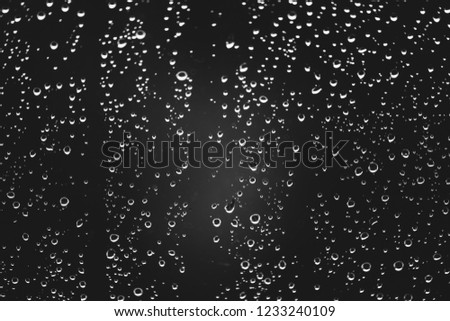 Dirty window glass with drops of rain. Atmospheric monochrome dark background with raindrops. Droplets and stains close up. Detailed transparent texture in macro with copy space. Rainy weather.