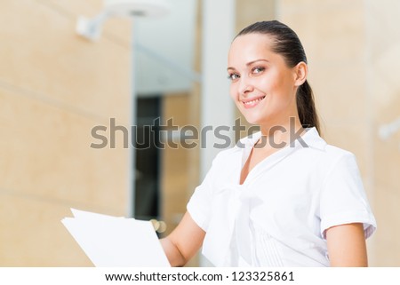 Portrait of a successful business woman in the office, holding papers and smile