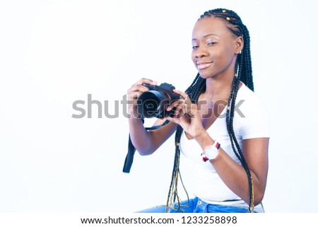 African girl takes pictures. Blacks fashion model. A girl with a sly look. A woman holds a camera in her hands. A woman wants to take a picture. African girl with pigtails.