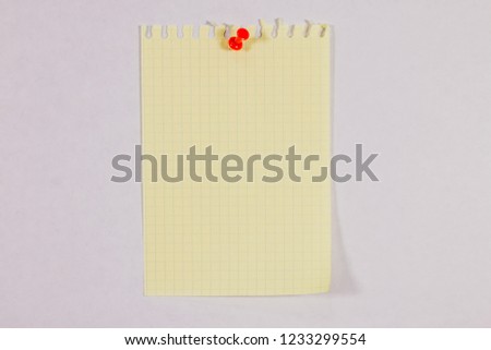 a piece of yellow notebook sheet in a cage attached with a push-button to a soft surface