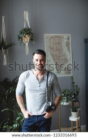 Handsome positive man with a photocamera at home against the background of the map. Traveler.