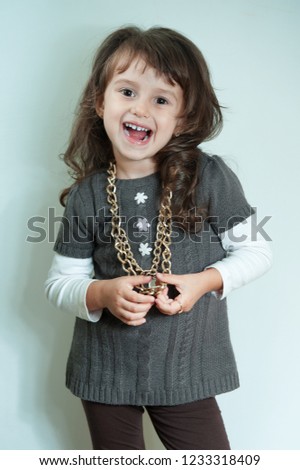 Happy little kid girl with gold chain on white background