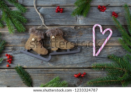 Red berries, spruce branches, candy cane, skates on a wooden background. Free space for text