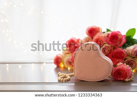 Rose fresh flowers bouquet on gray table by the window with heart gift box