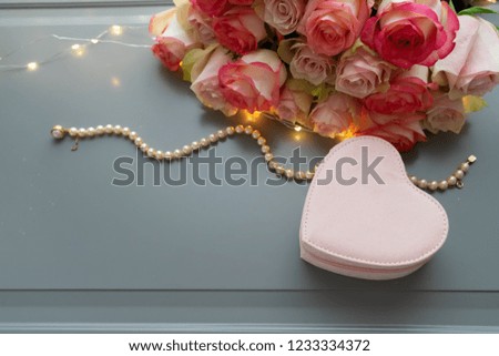 Rose fresh flowers bouquet with heart gift box on gray table from above, flat lay scene