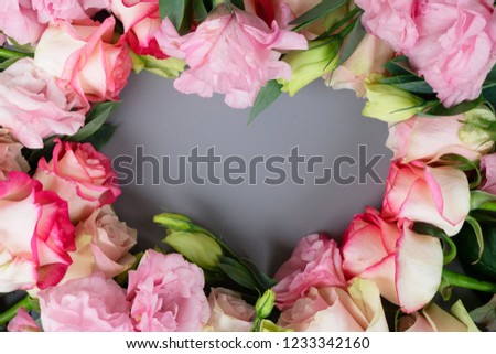 Rose fresh flowers on gray table from above, flat lay frame in shape of heart with copy space