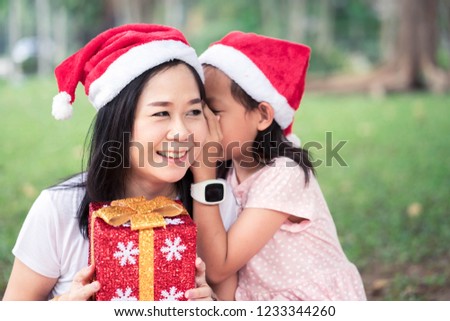 Asian Daughter whispers her mom in Christmas day or Xmas celebrate