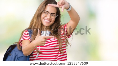 Young beautiful brunette student woman wearing headphones and backpack over isolated background smiling making frame with hands and fingers with happy face. Creativity and photography concept.
