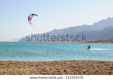 kite surfer in lagoon surrounded by desert mountains