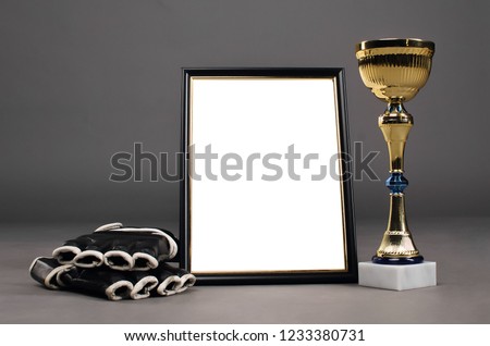 Empty photo frame with copy space for fighting winner, boxing gloves and golden award cup isolated on gray studio background.