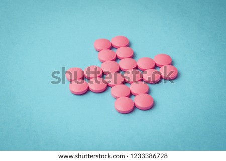 Cross of pink pills on blue background. Toned