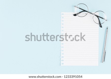one blank sheet with pen and glasses on blue background top view, spiral notepad blank empty sheet. flat lay of office concept